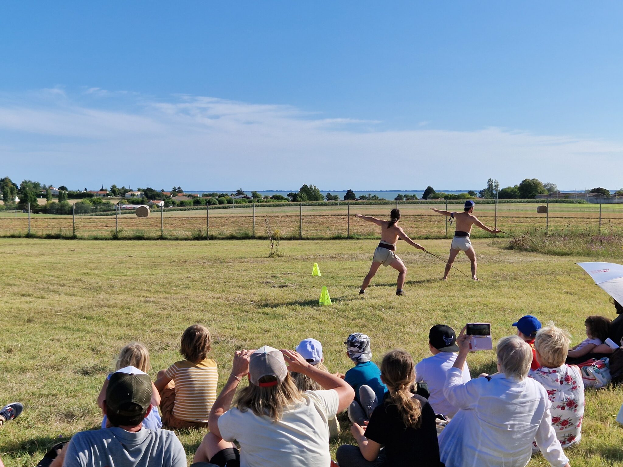 Deux sportifs se préparent à lancer le javelot devant le public et devant l'estuaire de la Gironde